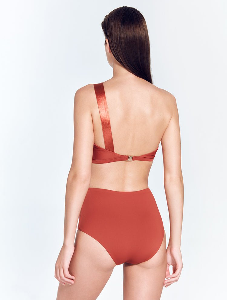 Back View: Model in Darika Red Ochre Bikini Top - MOEVA Luxury Swimwear, One Shoulder Swim Top, Comfort and Sportive Swim Top, Gold Clasps at the Back, Lycra XtraLife® Certificate, Italian Fabric, MOEVA Luxury Swimwear
