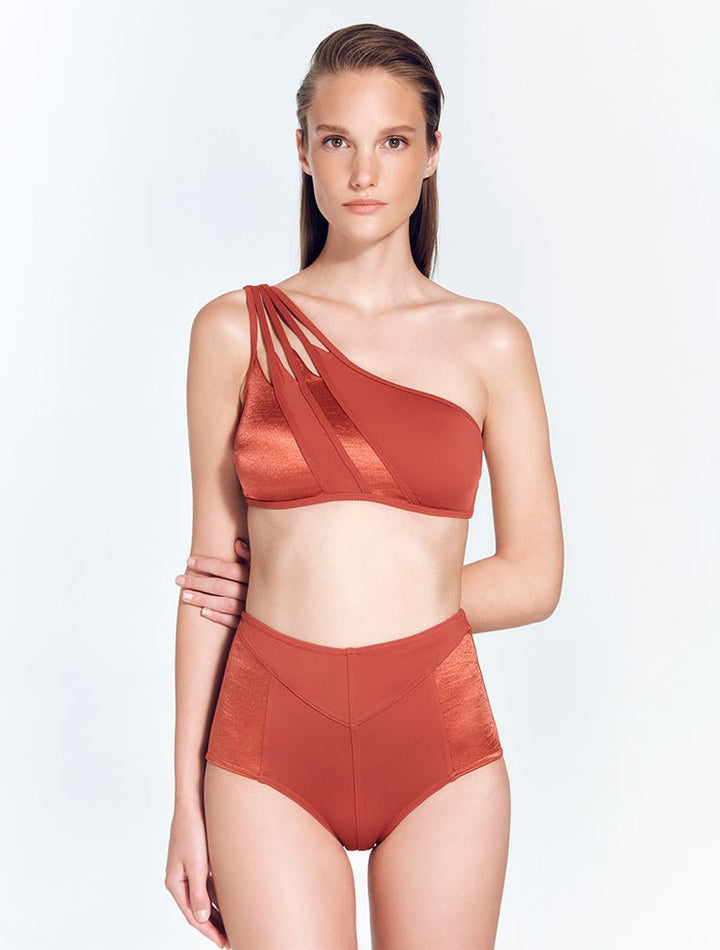 Front View: Model in Darika Red Ochre Bikini Top - MOEVA Luxury Swimwear, One Shoulder, Cutout Detail Straps, Matte Satin Contrast, MOEVA Luxury Swimwear
