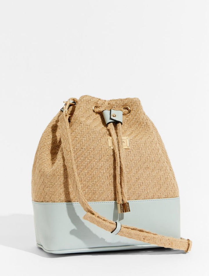Front View of Fiorella Blue Bag - MOEVA Luxury  Swimwear, Bucket Bag, Gold Dipped Moeva Logo Bar On Front, Drawstring Top, Leather Pocket, Shoulder Bag, Faux Leather Trim and Lining100% Straw, MOEVA Luxury  Swimwear     