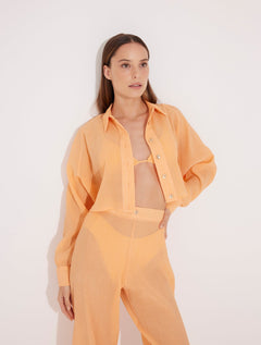 Front View: Model in Jacinta Orange Shirt - MOEVA Luxury Swimwear, Cropped Shirt, Button Fastening Through Front, Soft Touch Fabric, Recycle Fabric MOEVA Luxury Swimwear