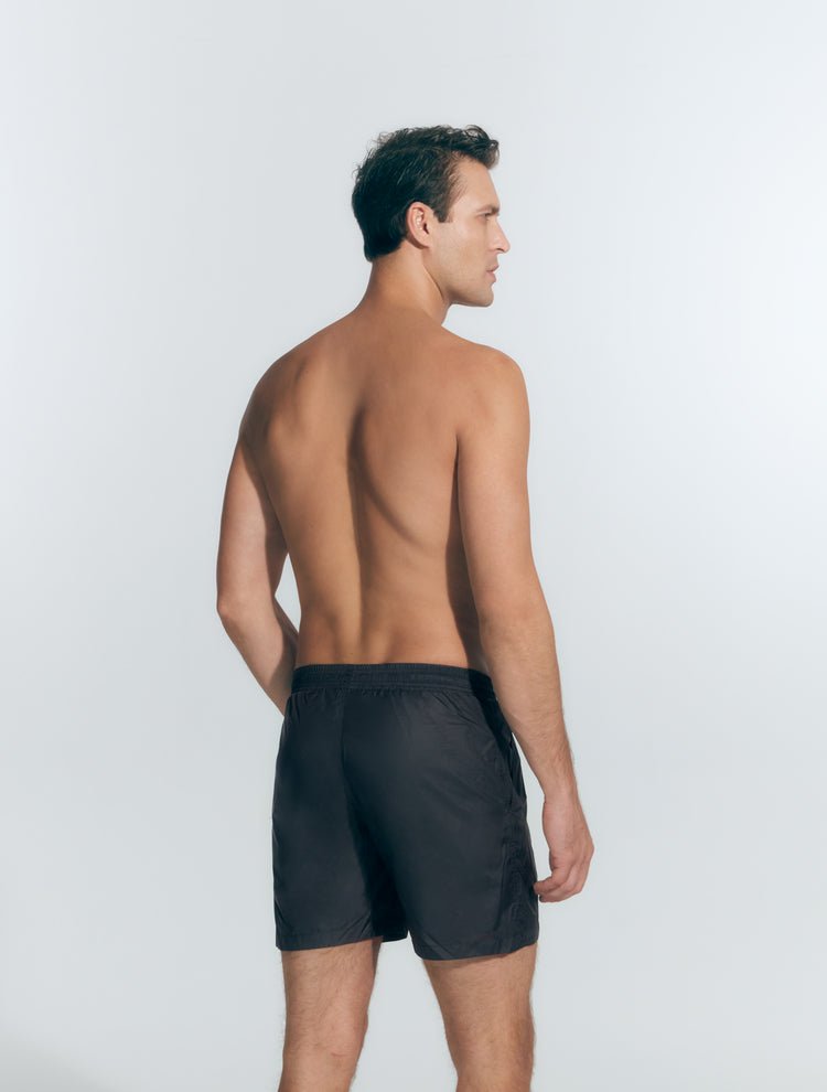 Back View: Model in Louis Black Shorts - MOEVA Luxury Swimwear, Men Swim Shorts, Nikel, Mid Length Swim Shorts, Fully Lined, Slim Fit, Quick Dry, MOEVA Luxury Swimwear
