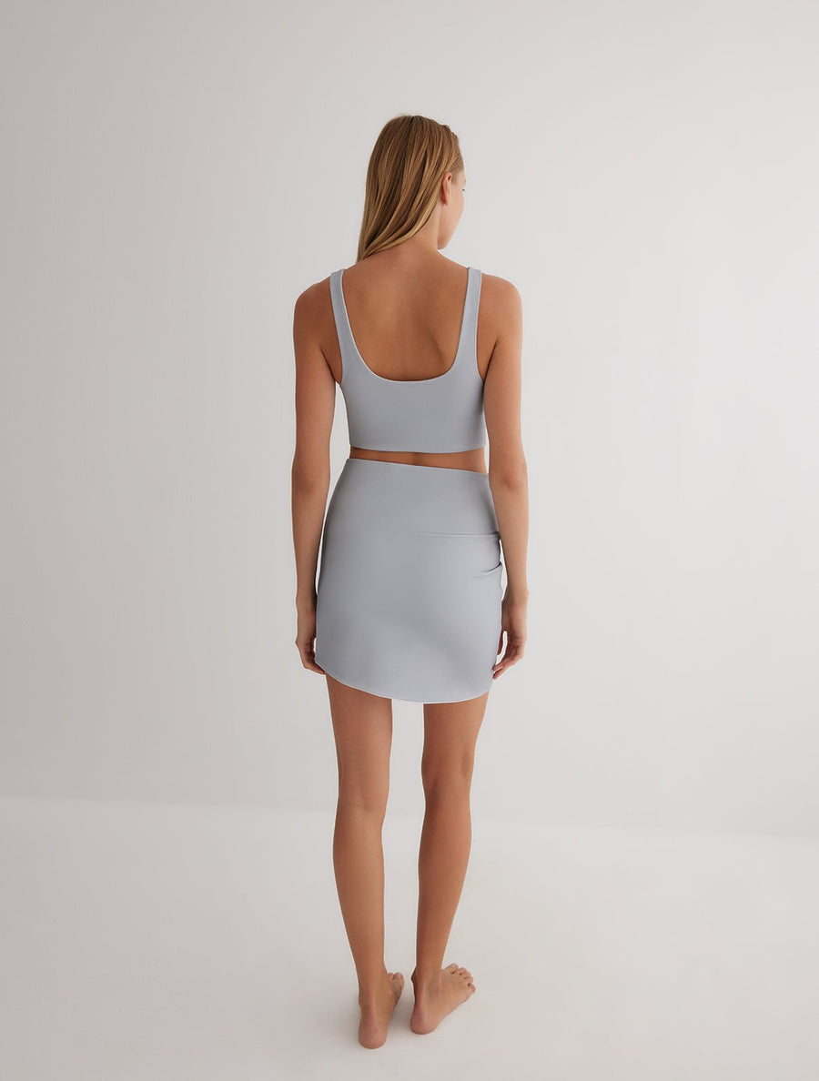 Back View: Model in Lupe Grey/White Skirt - MOEVA Luxury Swimwear, Mid-Thigh Length, Stretchy Fabric, MOEVA Luxury Swimwear