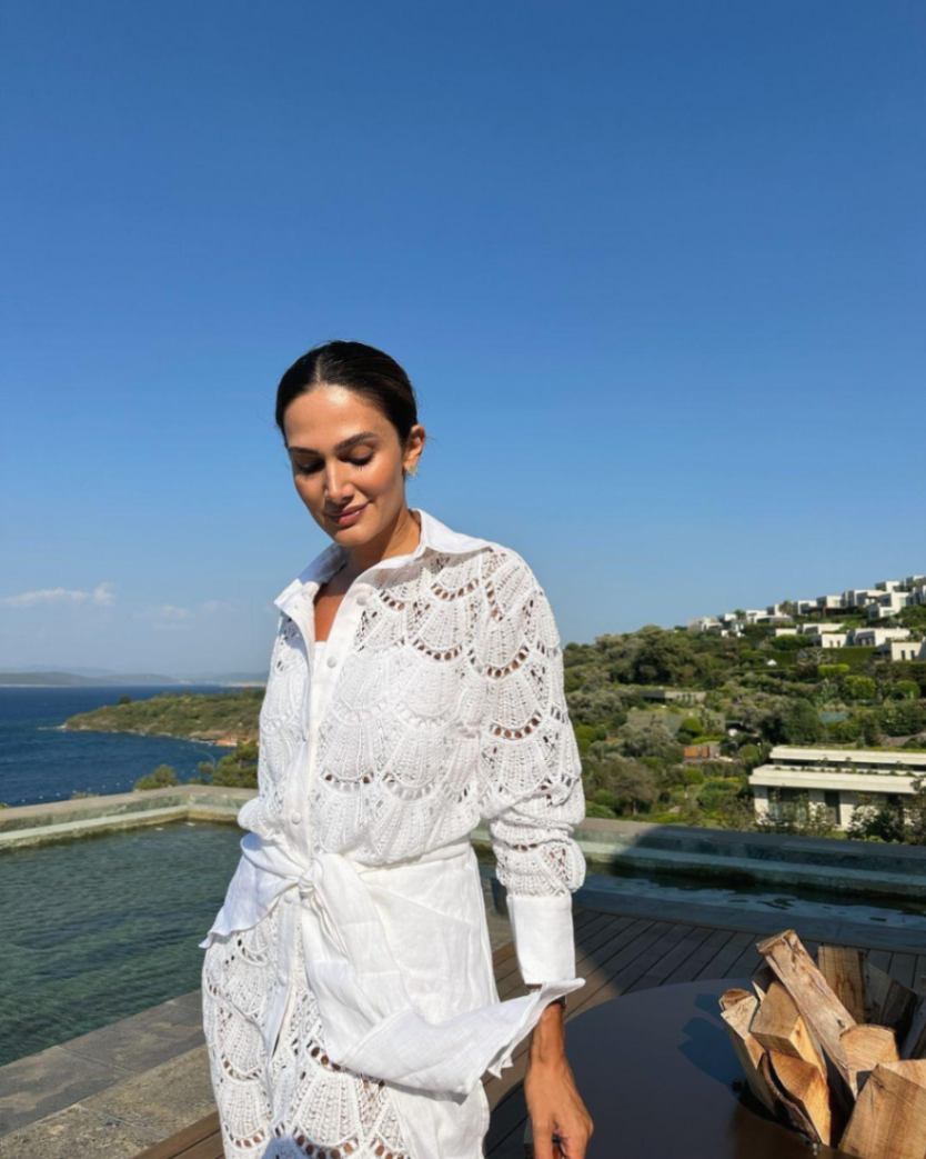 "Model wearing the Nayeli White Dress from the front, showcasing the broderie anglaise fabric, button front, and self-tie waist."