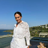 "Model wearing the Nayeli White Dress from the front, showcasing the broderie anglaise fabric, button front, and self-tie waist."