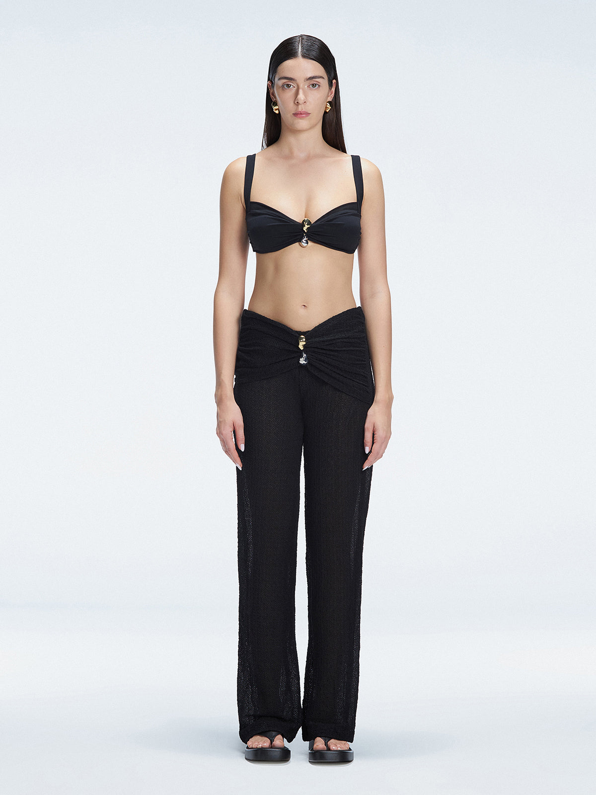 Front view of model wearing Angelique Black High-Rise Pants with layered panel and gold hoop accessory.
