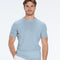 Man wearing a light blue shirt and white pants on a white background