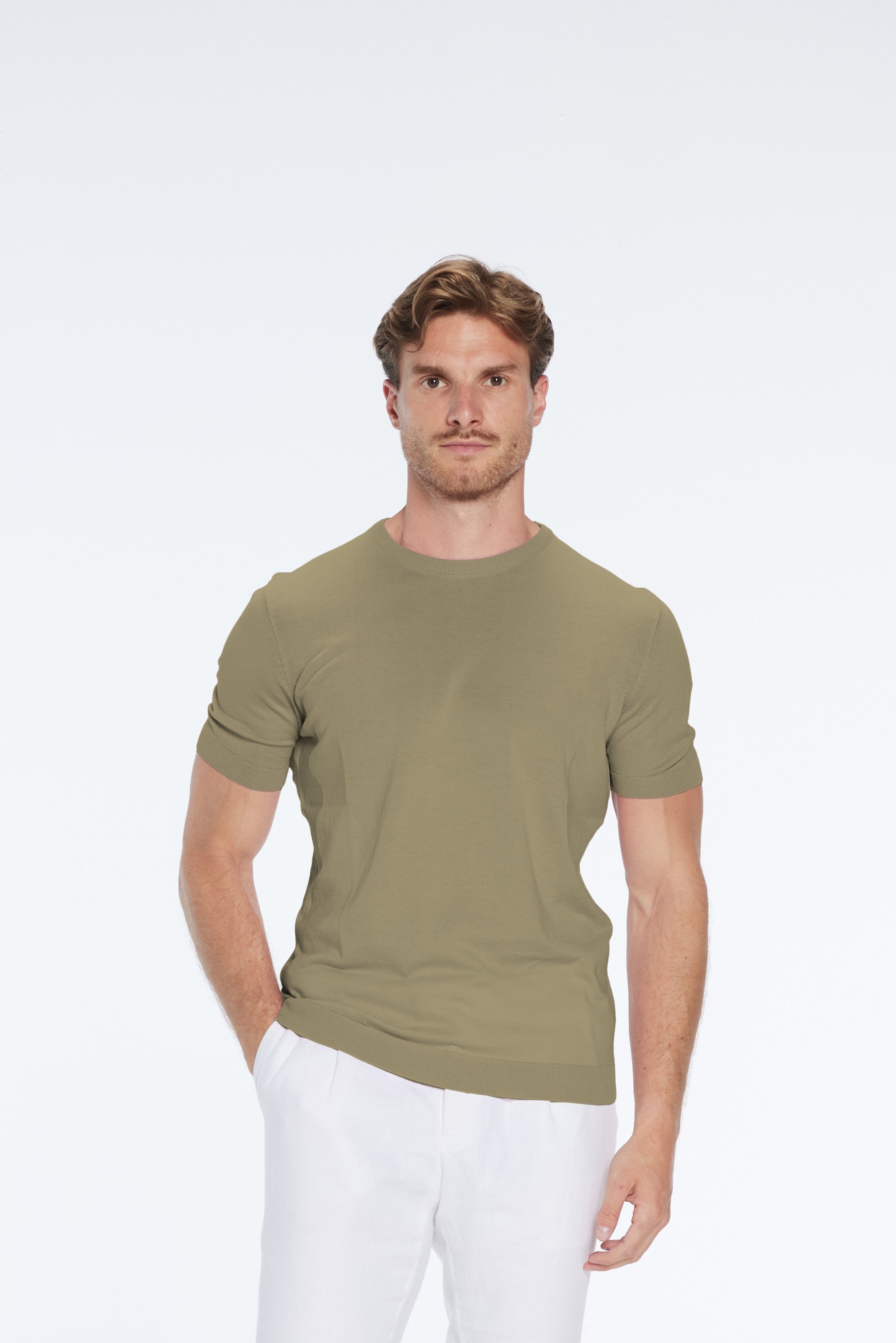Man wearing a green t-shirt and white pants on a white background