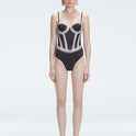 Front view of model wearing Camilla Black Optical Swimsuit with bandeau cut and boned torso for support.
