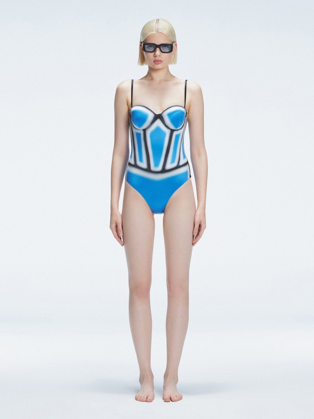 Front view of model wearing Camilla Blue Optical Swimsuit with bandeau cut and boned torso for support.
