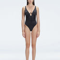 "Model wearing the Emma Black Underwired Swimsuit with a ruched front and moderate bottom coverage, standing poolside."
