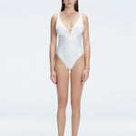 "Model wearing the Emma White Underwired Swimsuit with a ruched front and moderate bottom coverage, standing poolside."
