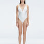 "Model wearing the Emma White Underwired Swimsuit with a ruched front and moderate bottom coverage, standing poolside."
