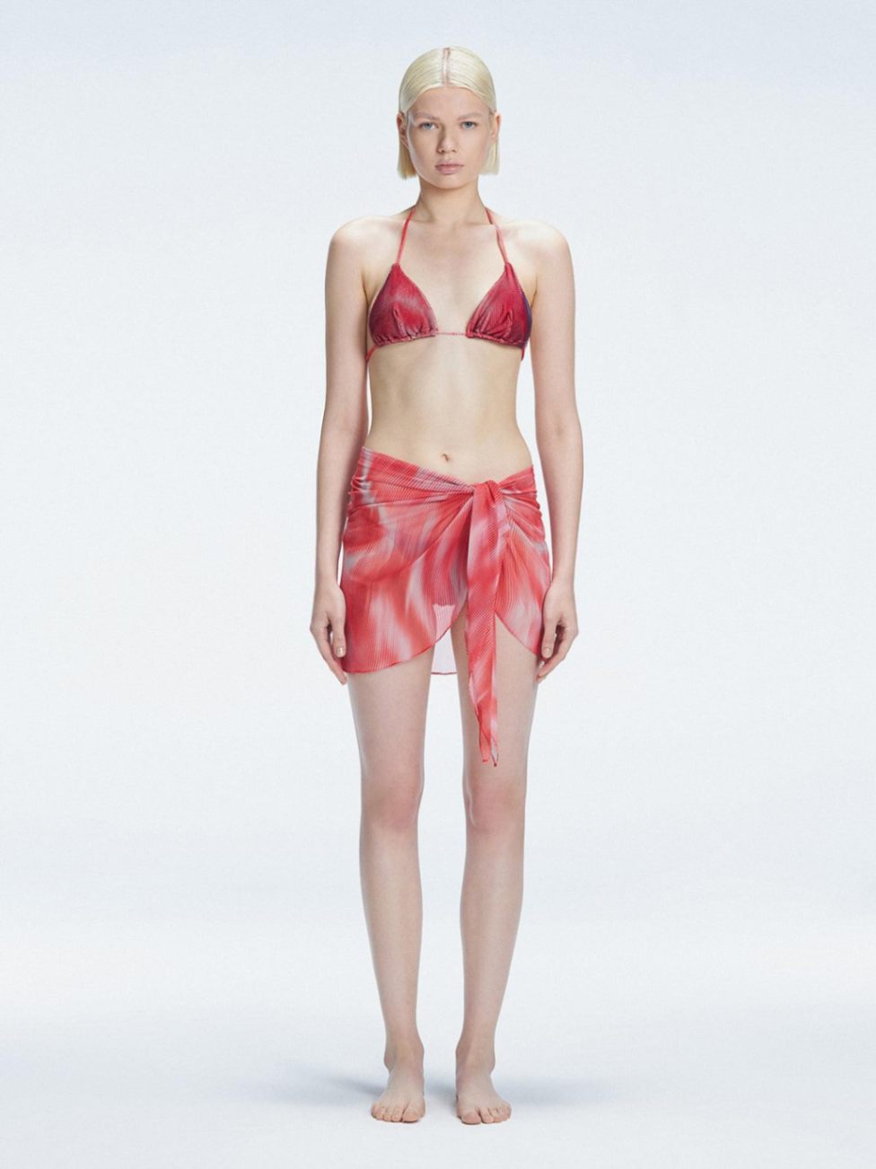 Model showcasing the Evita Red Sonar Cover-Up with front tie, radiating elegance at the beach."