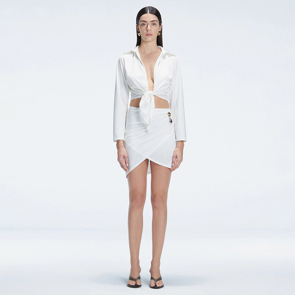 Greta White Long Sleeve Tie Front Shirt and Antonia White High-Waist Wrap Mini Skirt | Moeva | Set | Each week unveils new pieces—luxury swimwear, fluid resort silhouettes, and elevated summer-to-evening essentials designed to carry you from coastal escapes to city nights.