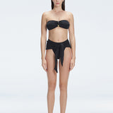 "Model wearing the Ilana Shiny Black Bikini Bottom from the front, showcasing the chic bandeau style and elegant buckle detail."
