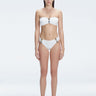 "Model wearing the Ilana White Bikini Bottom from the front, showcasing the chic bandeau style and elegant buckle detail."

