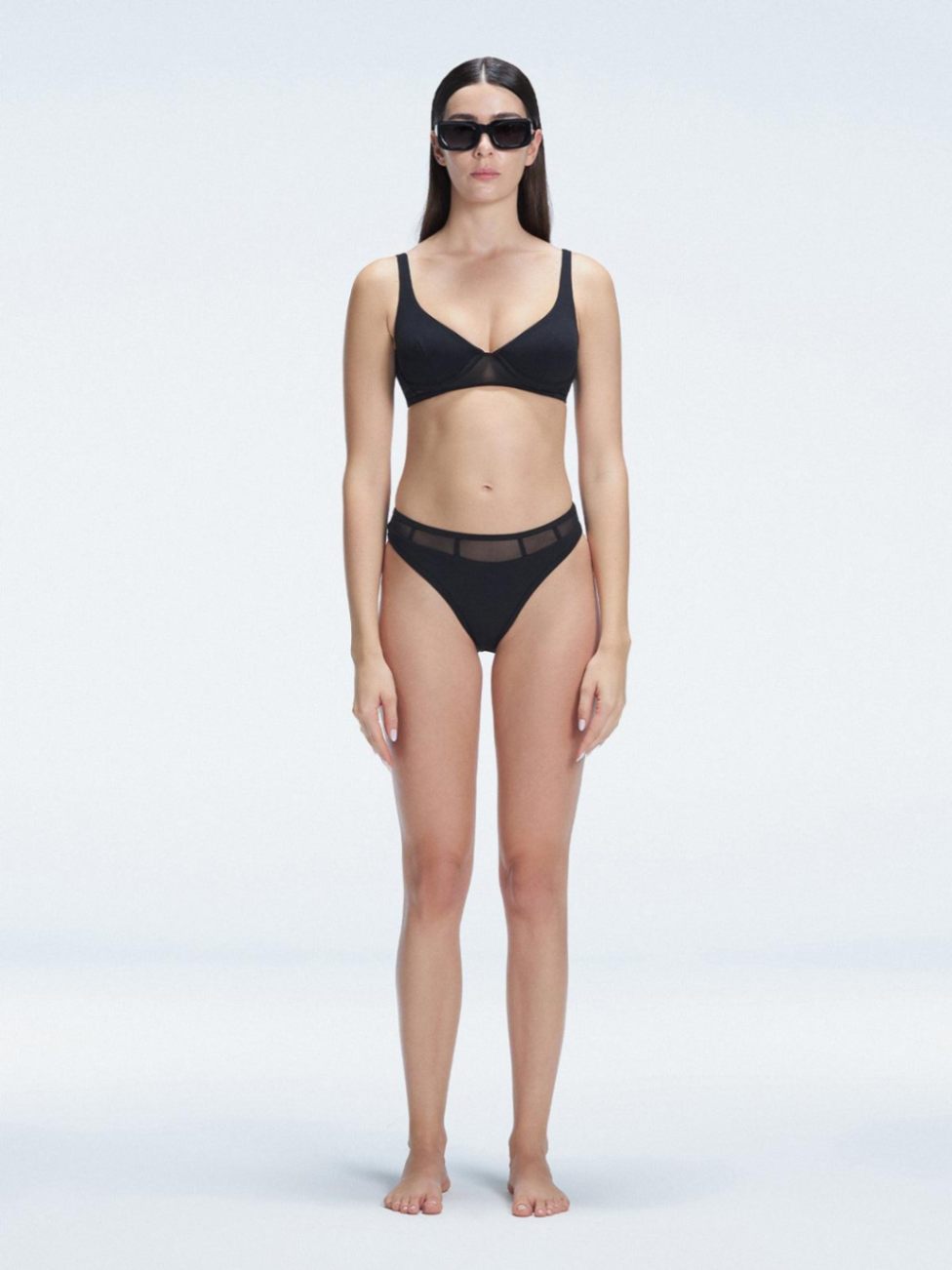 "Model wearing the Lorelai Black Bikini Set with a high-waisted design and mesh detail, posing by the pool."
