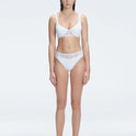 "Model wearing the Lorelai White Bikini Bottom with a high-waisted design and mesh detail, posing by the pool."
