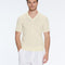 Man wearing a light yellow V-neck sweater and white pants on a white background