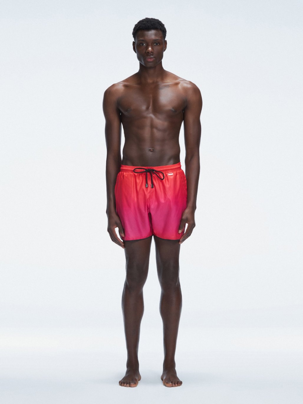 Model wearing Griffin Red Gradient Swim Shorts with pink-red print and sporty piping.