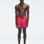 Model wearing Griffin Red Gradient Swim Shorts with pink-red print and sporty piping.