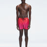 Model wearing Griffin Red Gradient Swim Shorts with pink-red print and sporty piping.