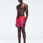 Model wearing Griffin Red Gradient Swim Shorts with side piping and elastic waistband.
