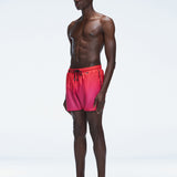 Model wearing Griffin Red Gradient Swim Shorts with side piping and elastic waistband.
