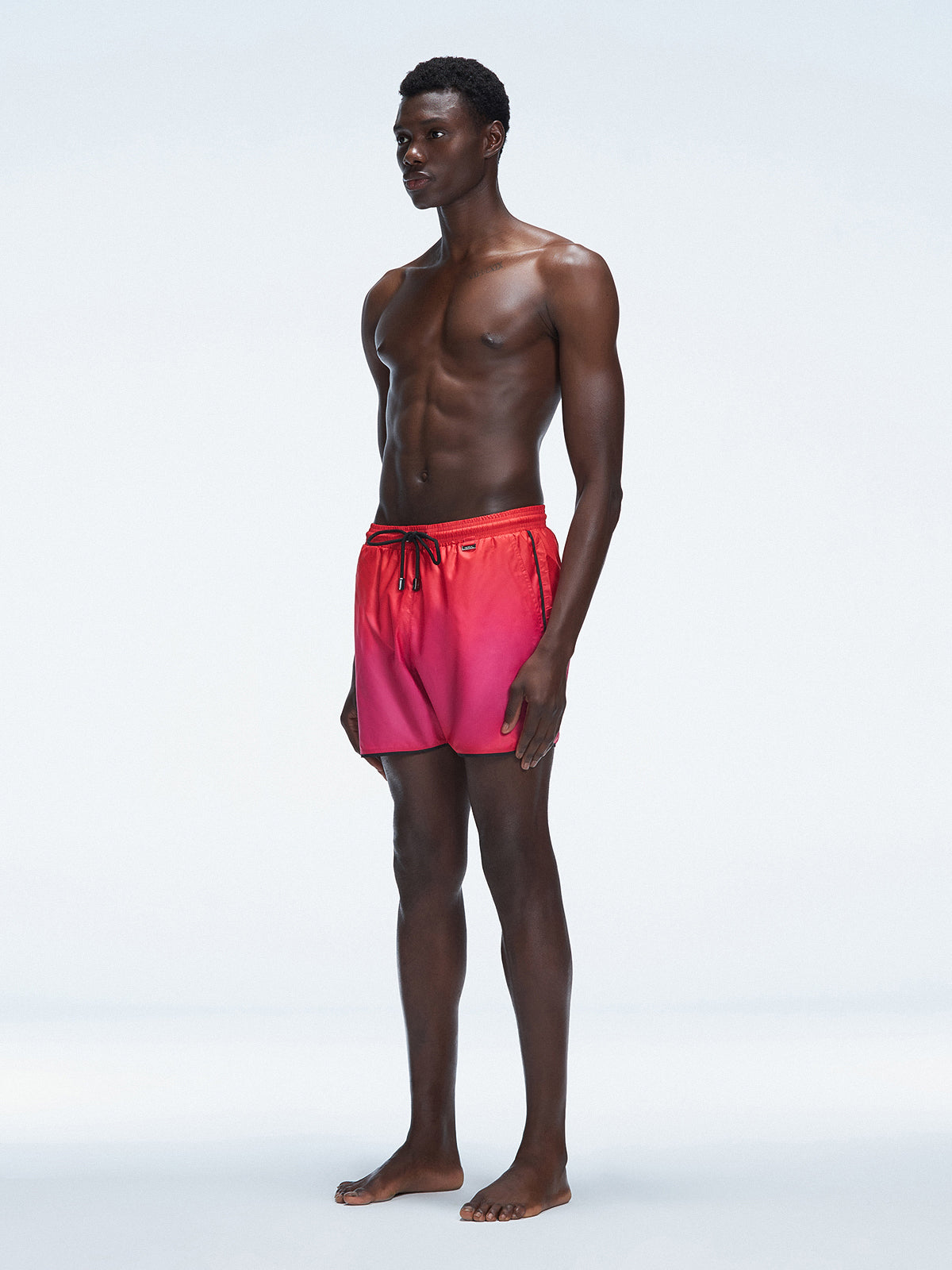 Model wearing Griffin Red Gradient Swim Shorts with side piping and elastic waistband.
