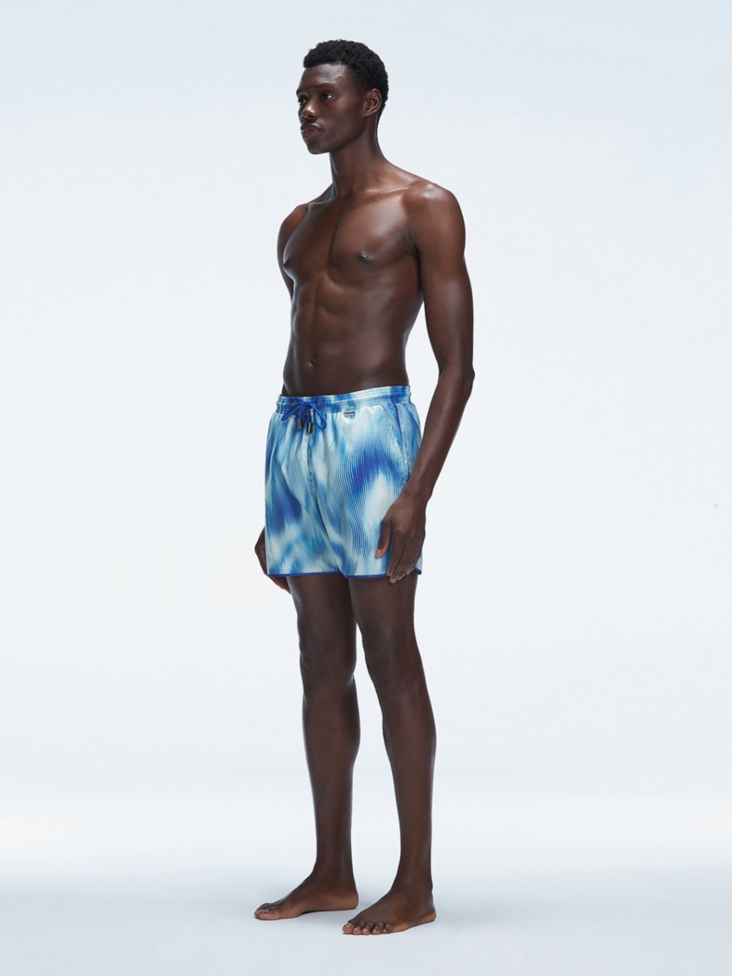 Model wearing Griffin Blue Swim Shorts with side piping and comfortable elastic waistband.
