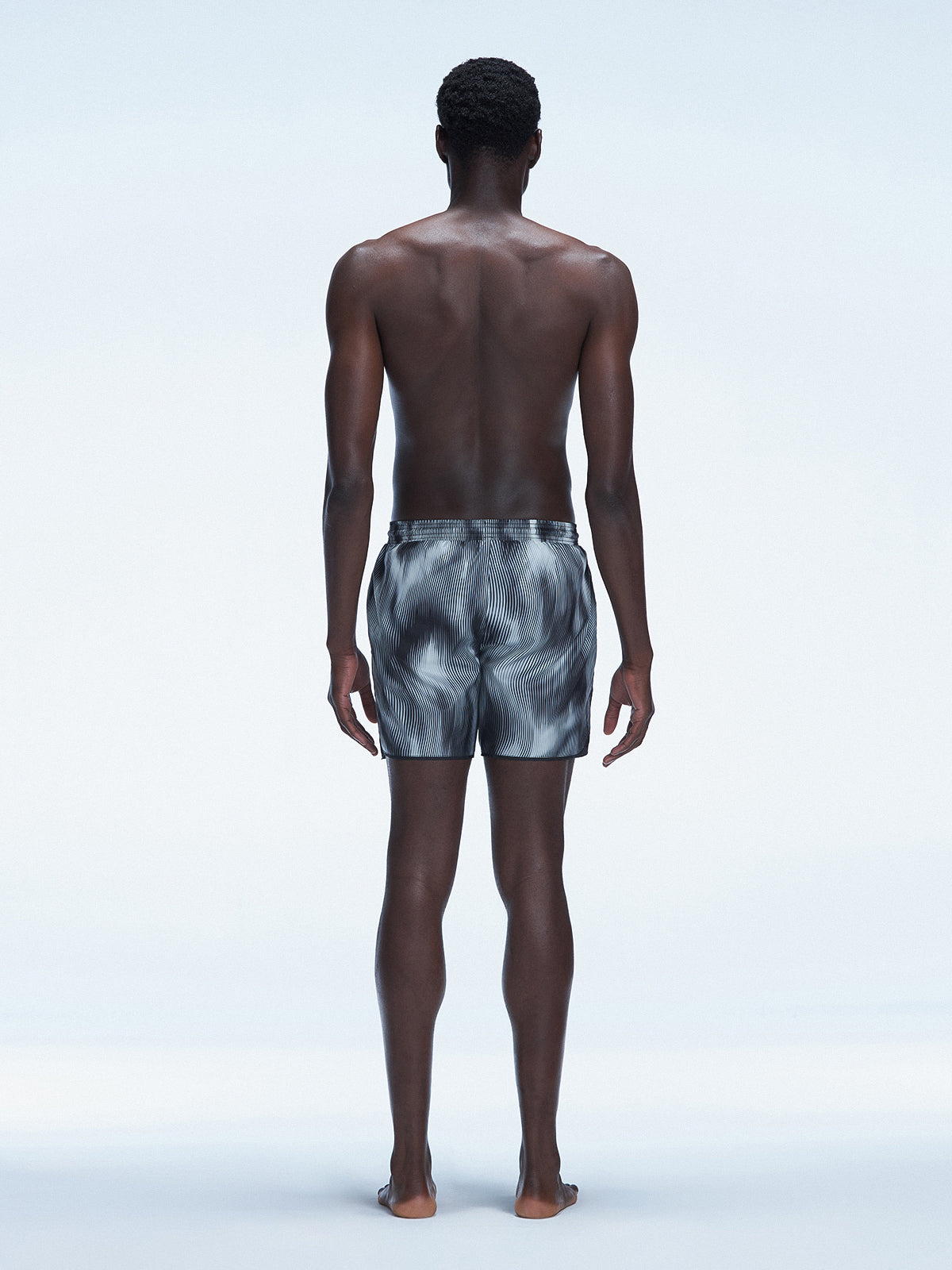 Back view of model wearing Griffin Black Sonar Swim Shorts, showcasing the bold black print and comfortable fit.
