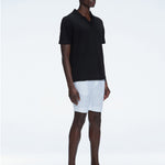 Side view of the Atticus Black Polo T-Shirt on a model, highlighting the open collar and sleek, tailored fit.
