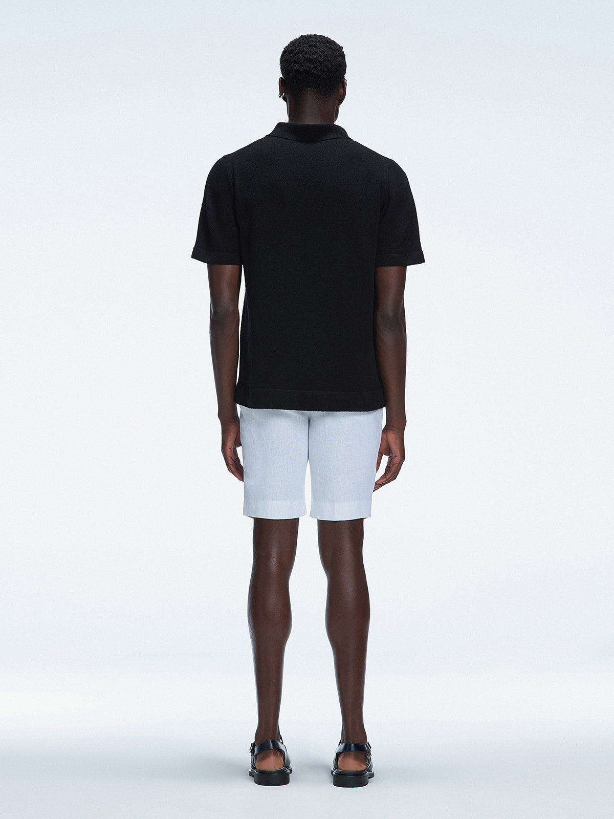 Back view of the model wearing the Atticus Black Polo T-Shirt, showcasing the slim fit and short sleeves.

