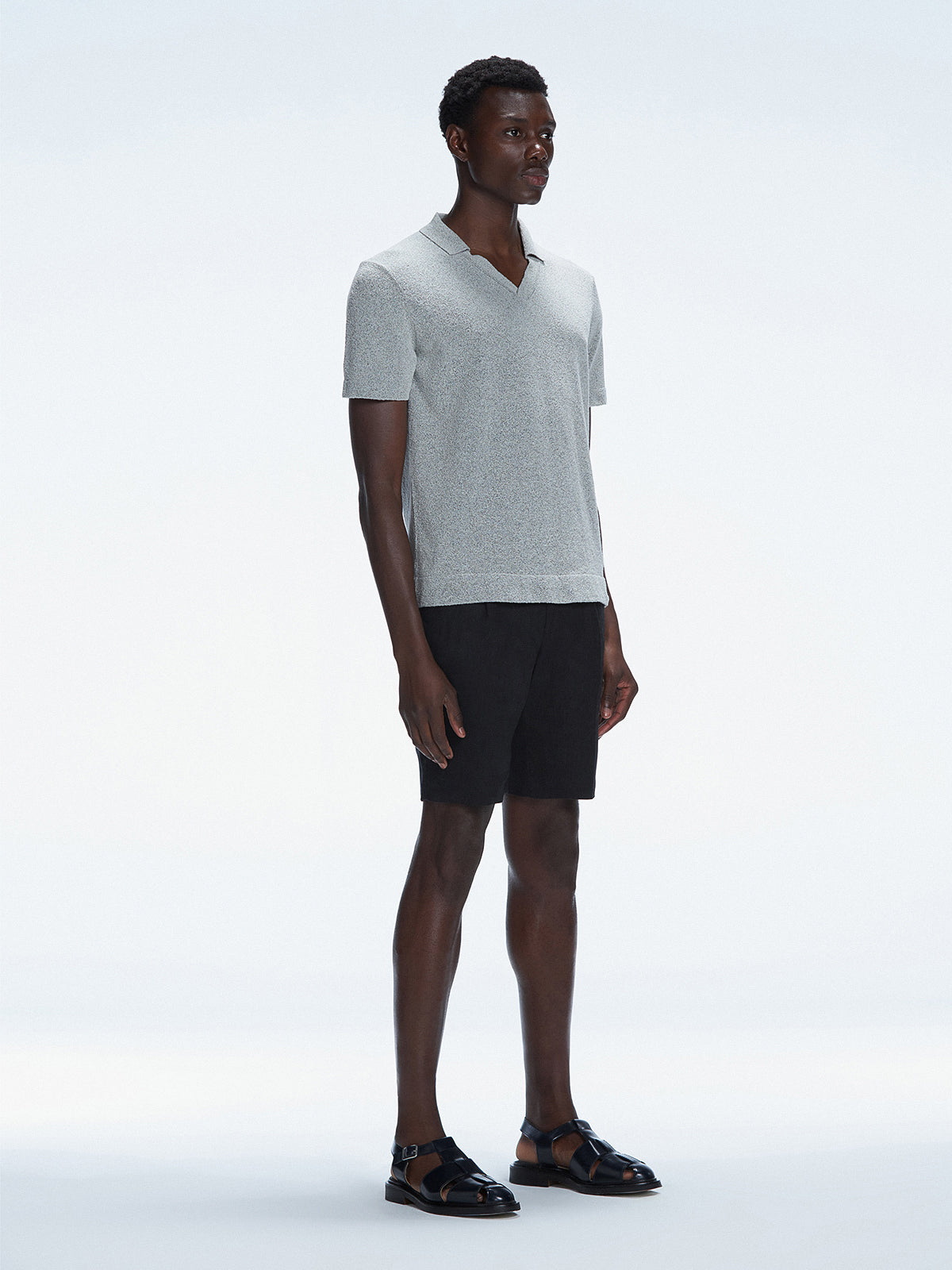 Side view of the Atticus Grey Polo T-Shirt on a model, highlighting the sleek open collar and short sleeves.
