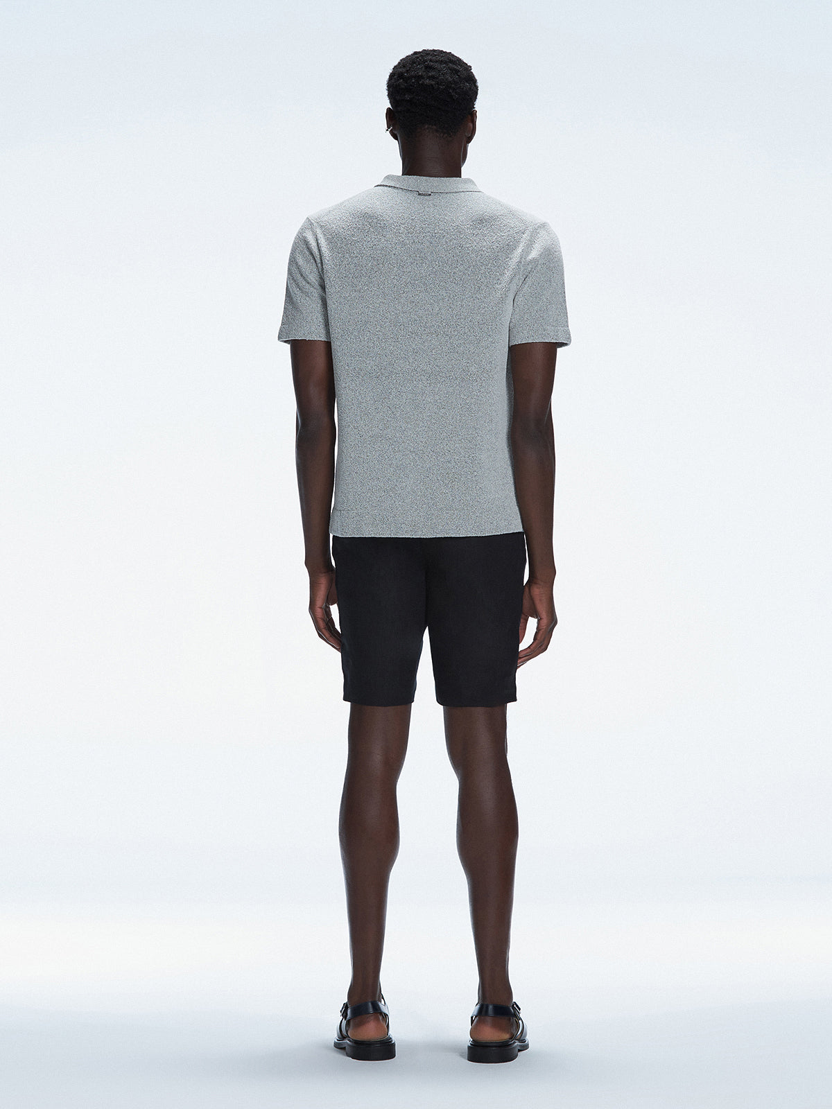 Back view of the model wearing the Atticus Grey Polo T-Shirt, showcasing the slim fit and short sleeves.
