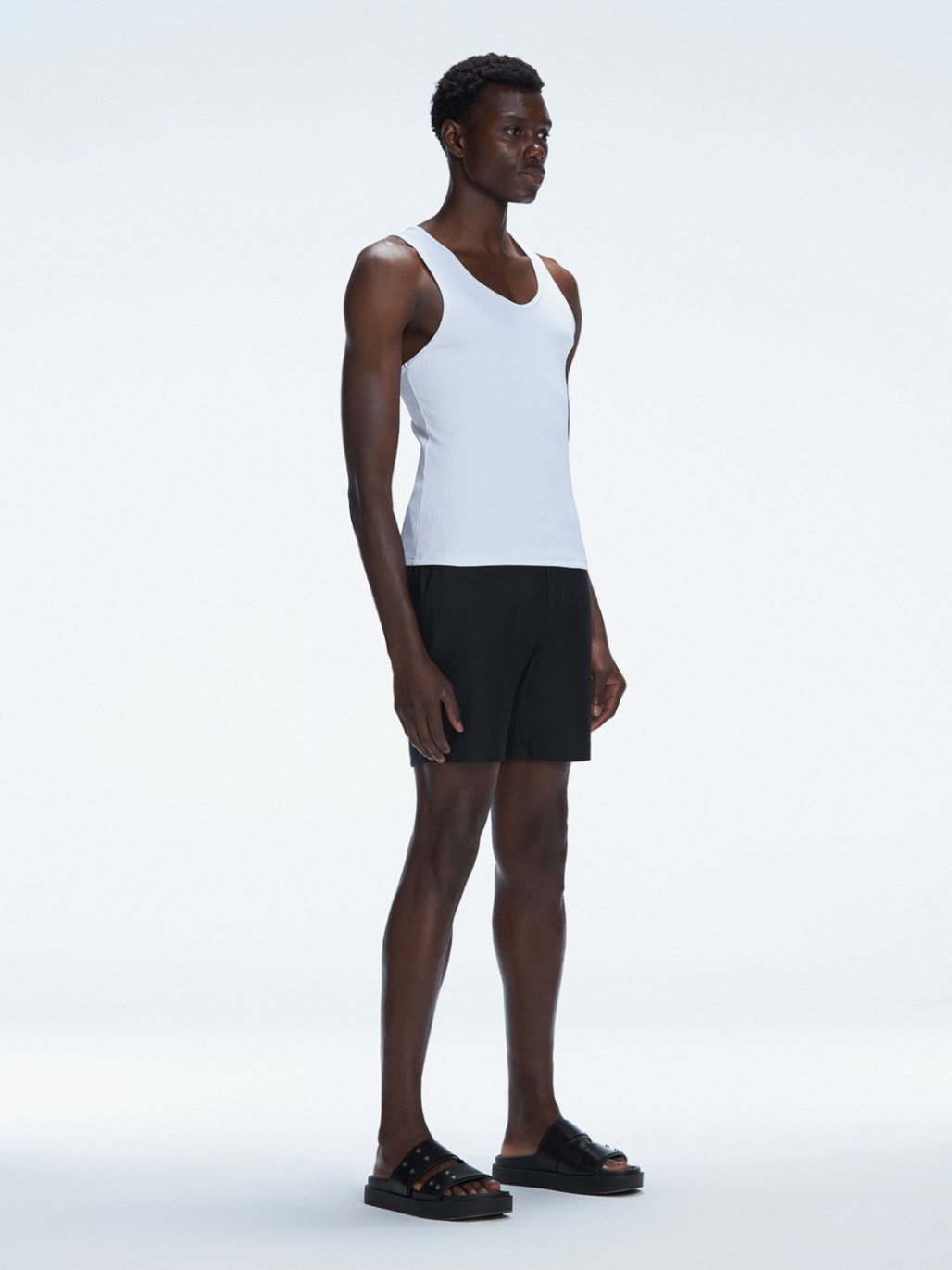 Side view of the model wearing the Phillip White Tank Top, highlighting the sleeveless design and sleek fit.
