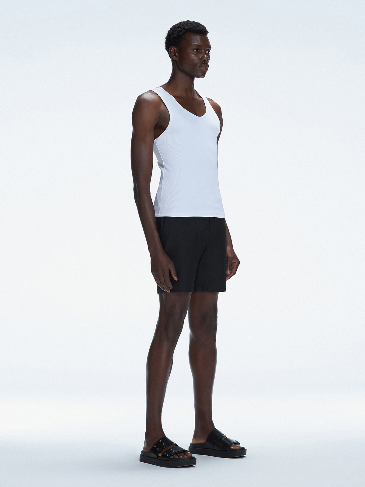 Side view of the model wearing the Phillip White Tank Top, highlighting the sleeveless design and sleek fit.
