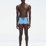 Model wearing Antonio Baby Blue/Blue Swim Trunks with a tight, form-fitting design.
