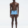 Model wearing Antonio Baby Blue/Blue Swim Trunks with a tight, form-fitting design.
