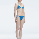 Side view of model showcasing the adjustable halterneck ties and bold 3D printed design on the Hermione Blue Bikini Top.
