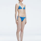 Side view of model showcasing the adjustable halterneck ties and bold 3D printed design on the Hermione Blue Bikini Top.
