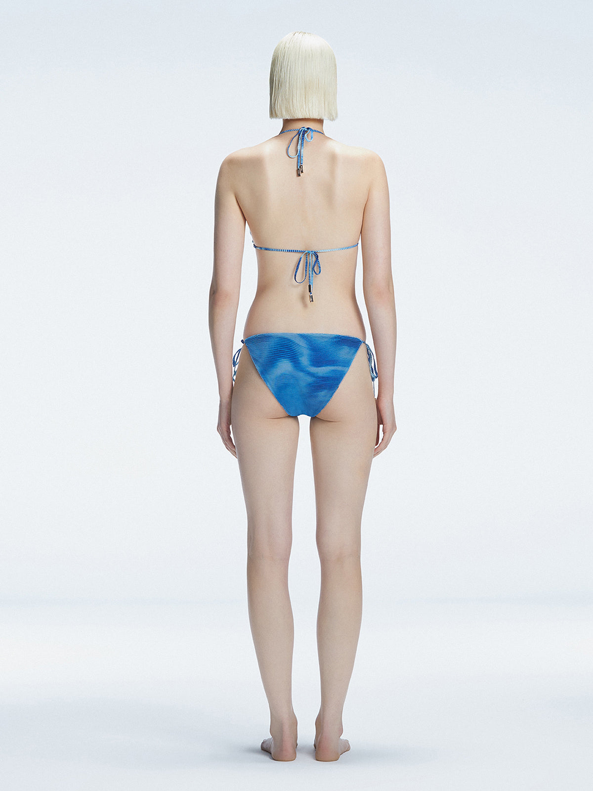 Back view of model wearing Hermione Blue Optical Bikini Set, highlighting the low-waist fit and sleek design.
