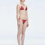 Side view of model showcasing the adjustable halterneck ties and bold 3D printed design on the Hermione Red Bikini Top.
