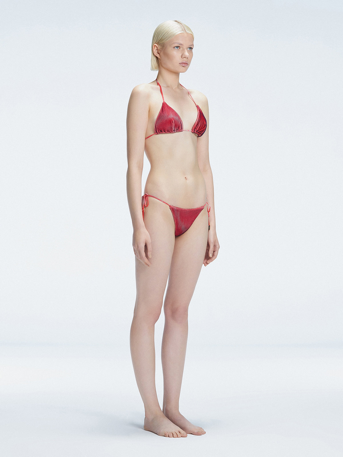 Side view of model showcasing the adjustable halterneck ties and bold 3D printed design on the Hermione Red Bikini Top.
