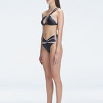 Side view of model showcasing the one-shoulder style and sleek fit of the Eva Black Bikini Top.
