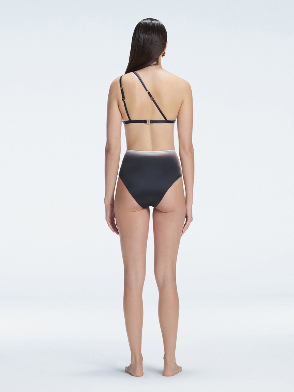 Back view of model wearing Eva Black Optical Bikini Top, highlighting the elegant one-shoulder design.
