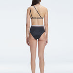 Back view of model wearing Eva Black Optical Bikini Top, highlighting the elegant one-shoulder design.
