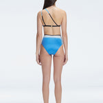 Back view of model wearing Eva Blue Optical Bikini Top, highlighting the elegant one-shoulder design.
