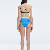 Back view of model wearing Eva Blue Optical Bikini Top, highlighting the elegant one-shoulder design.
