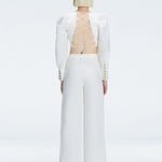Back view of model wearing Valencia White Pants, highlighting the crisscross back straps and high-waisted fit.
